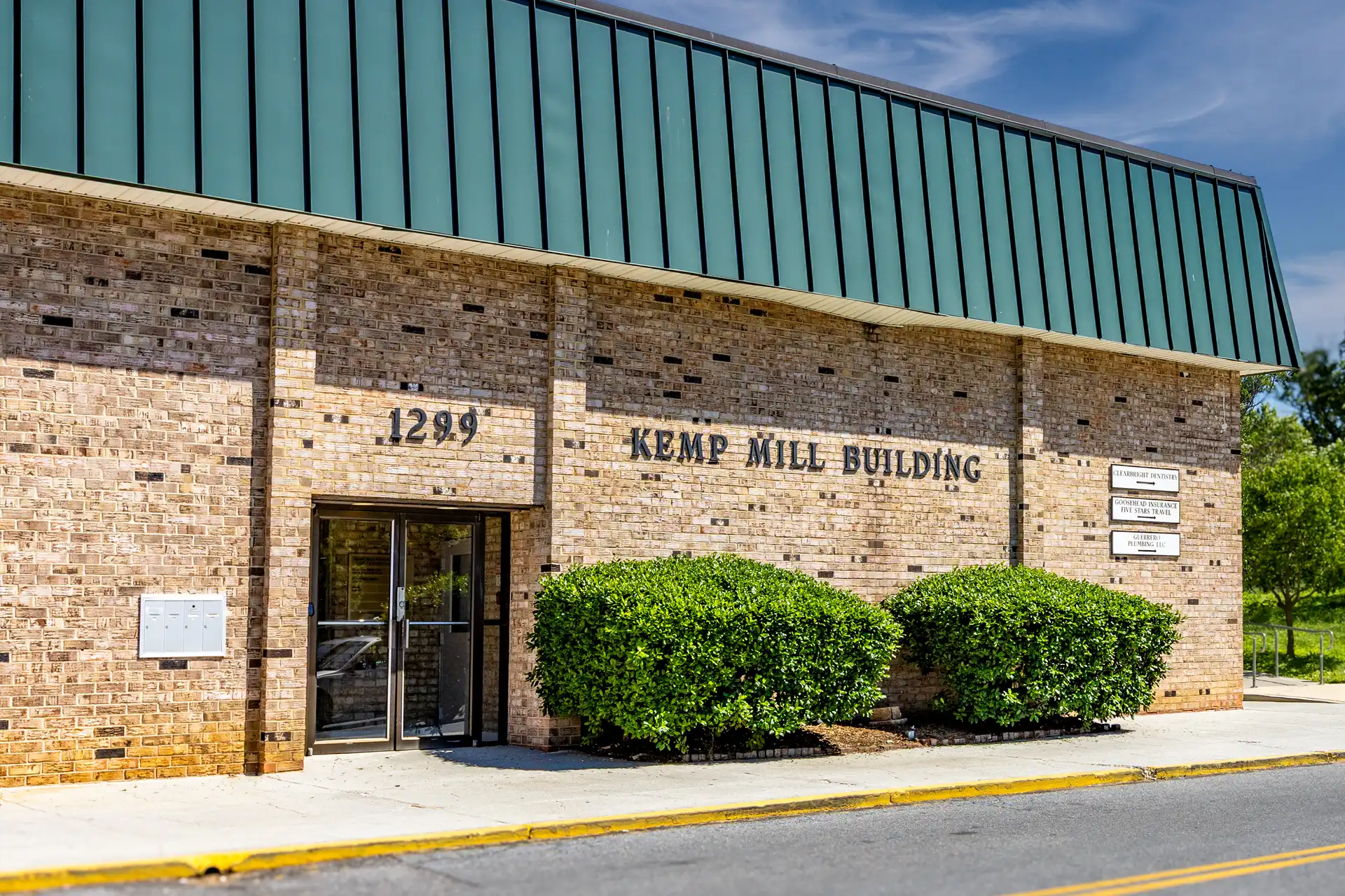 An exterior picture of a brick building at Kemp Mill Shopping Center where there are retail commercial spaces for lease​ in Maryland.